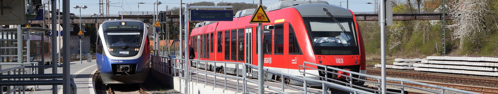 Rechts: Roter Zug der Deutschen Bahn und blau-weß-gelber Zug der NordWestBahn (links) stehen auf gleicher Höhe in einer Station