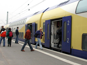 Fahrg&auml;ste steigen in gelb-blau-wei&szlig;en Zug ein